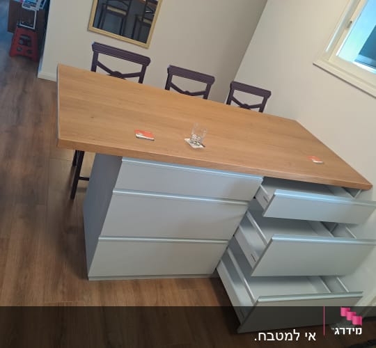 אי מטבח עם מגירות פתוחות ומשטח עץ